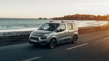 Citroën Berlingo estacionado con vista lateral, fondo playa al atardecer.