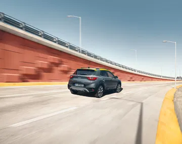 Vista dinámica de la parte trasera y lateral del Kia Stonic en movimiento.