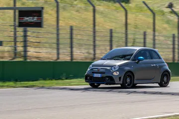 Vista lateral del Abarth 595 compitiendo en pista, destacando su diseño deportivo.