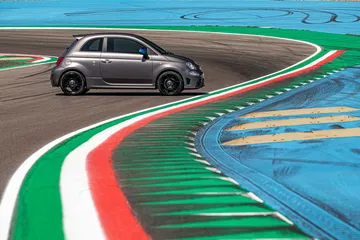 Vista lateral del Abarth 595 tomando una curva en circuito, realzando su perfil deportivo.
