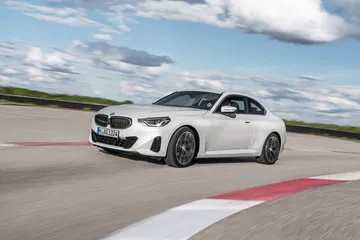 Vista dinámica del BMW Serie 2 en pista, enfatizando su perfil y frontal agresivo.