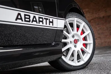Vista cercana de la llanta y el emblema 'ABARTH' en el lateral del coche.