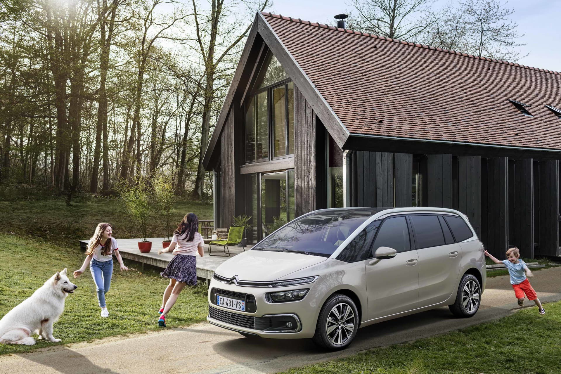Vista delantera y lateral del Citroën Grand C4 SpaceTourer con una familia disfrutando al aire libre.