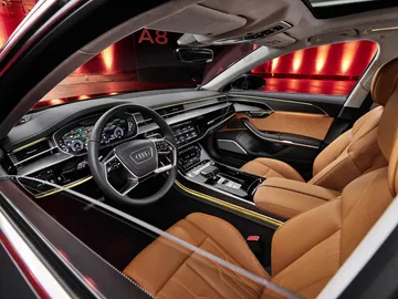 Vista lateral de la lujosa cabina del Audi A8 con asientos de cuero y volante multifunción.
