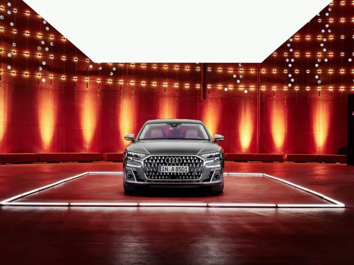 Audi A8 en exhibición con iluminación destacando su frontal imponente.