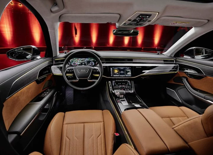 Vista delantera del habitáculo del Audi A8, resaltando su lujosa tapicería y tecnología de vanguardia.