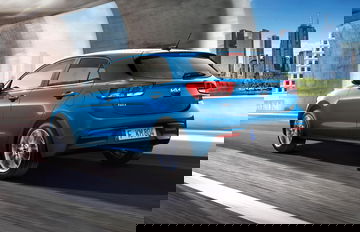 Vista dinámica de un Kia Rio en color azul, destacando su diseño trasero y lateral.