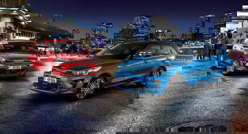 Vista dinámica del Kia Rio en ambiente urbano nocturno, destacando su diseño frontal y lateral.