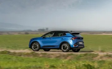 Vista dinámica del Kia Sportage en un entorno campestre, destacando su perfil.