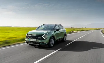 Nuevo Kia Sportage en dinámica por carretera, diseño frontal y perfil lateral.