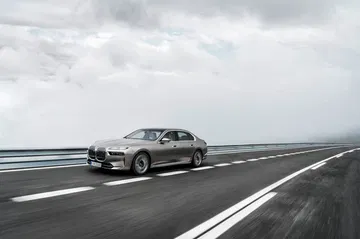 BMW i7 en dinámica lateral sobre carretera, perfil elegante y moderno.