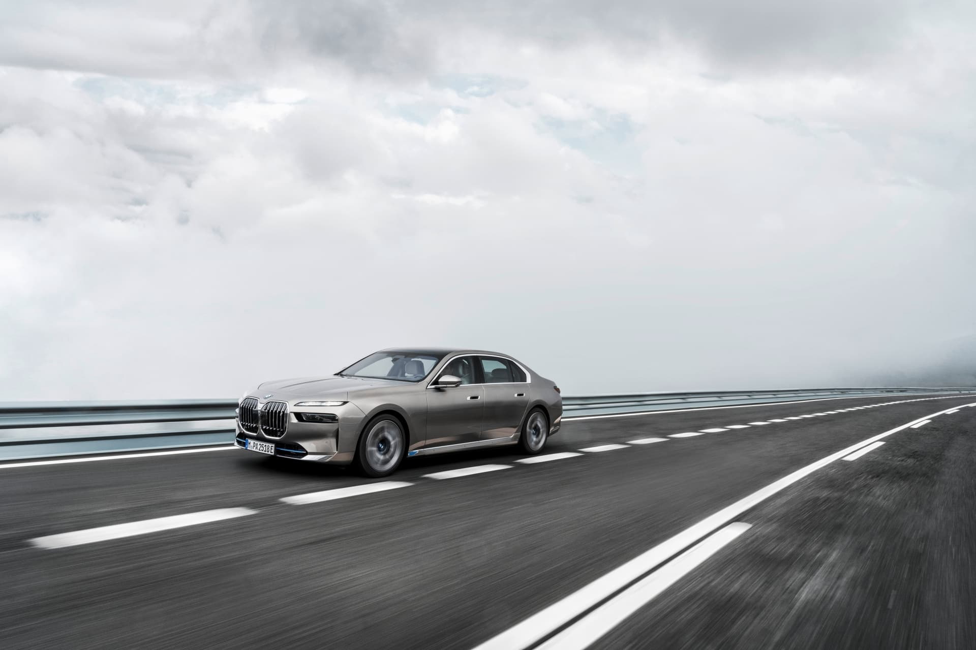 BMW i7 en dinámica lateral sobre carretera, perfil elegante y moderno.