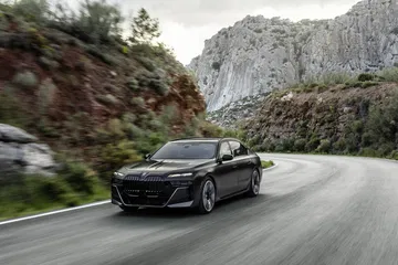 Vista dinámica del BMW Serie 7 en carretera de montaña, exhibiendo su diseño aerodinámico.