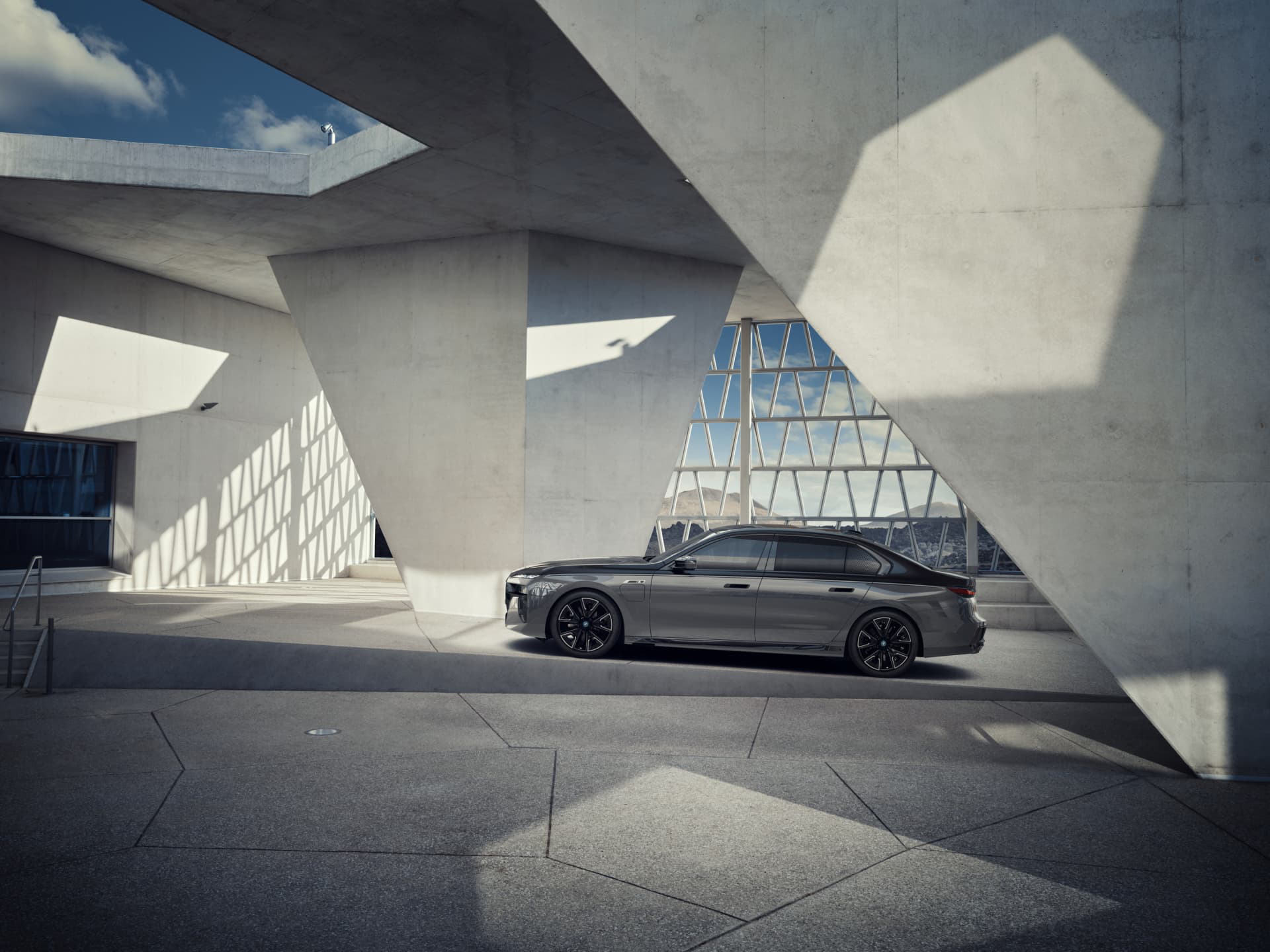 Vista lateral de un BMW Serie 7 contrastando con arquitectura contemporánea.