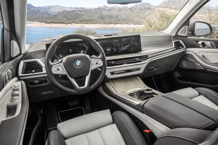 Vista lateral del interior lujoso del BMW X7, destacando volante y consola central.