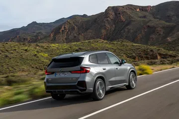 Vista lateral del BMW X1 en movimiento por una carretera de montaña.
