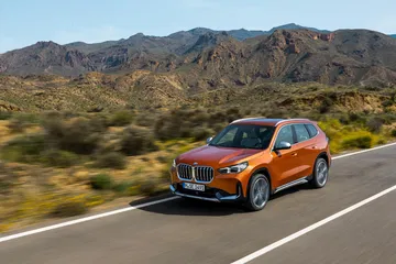 Vista dinámica del BMW X1 en carretera, perfil resaltando su diseño lateral.