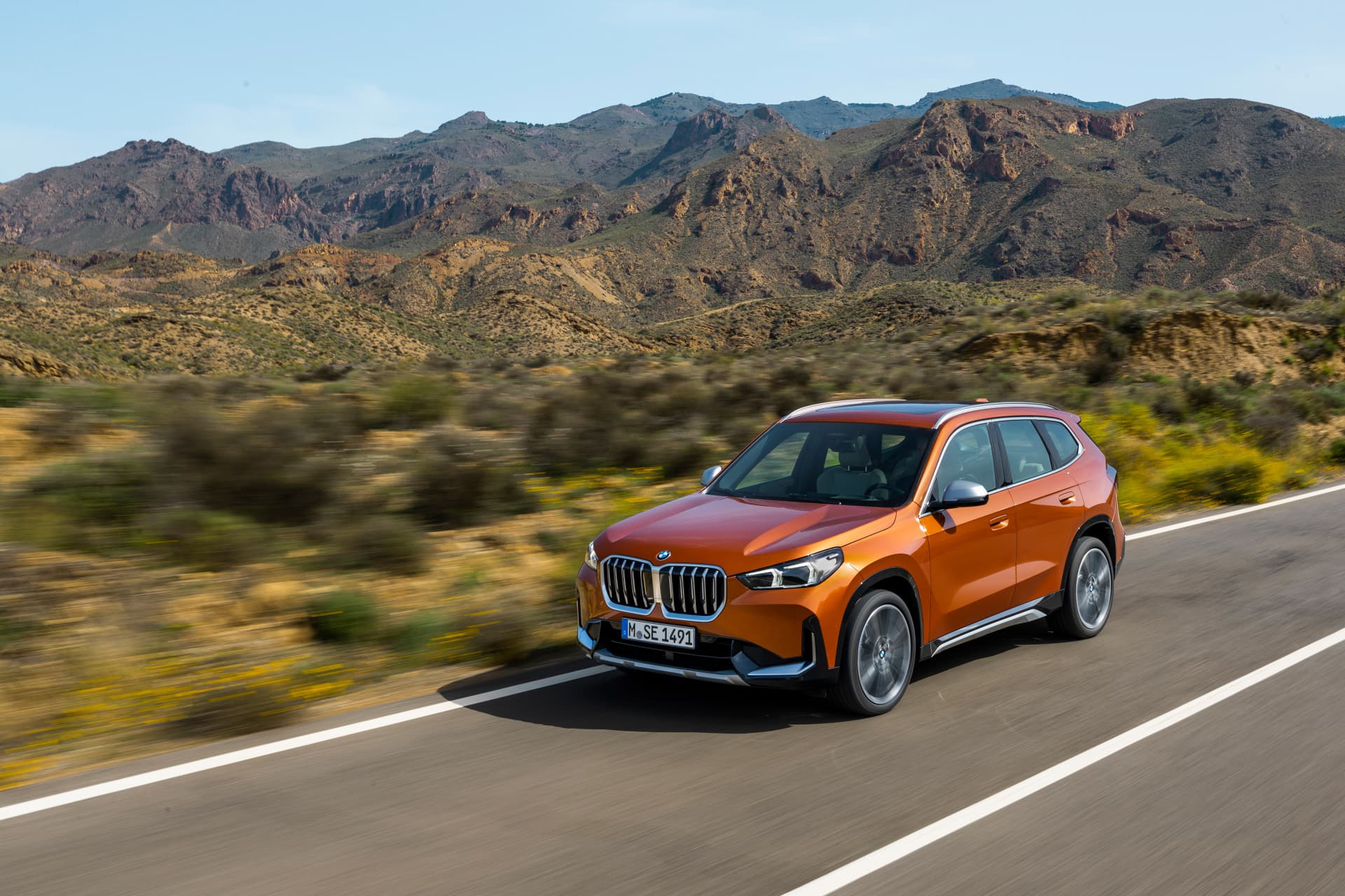 Vista dinámica del BMW X1 en carretera, perfil resaltando su diseño lateral.