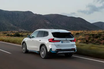 Vista dinámica del BMW X1 circulando por una carretera con paisaje montañoso.