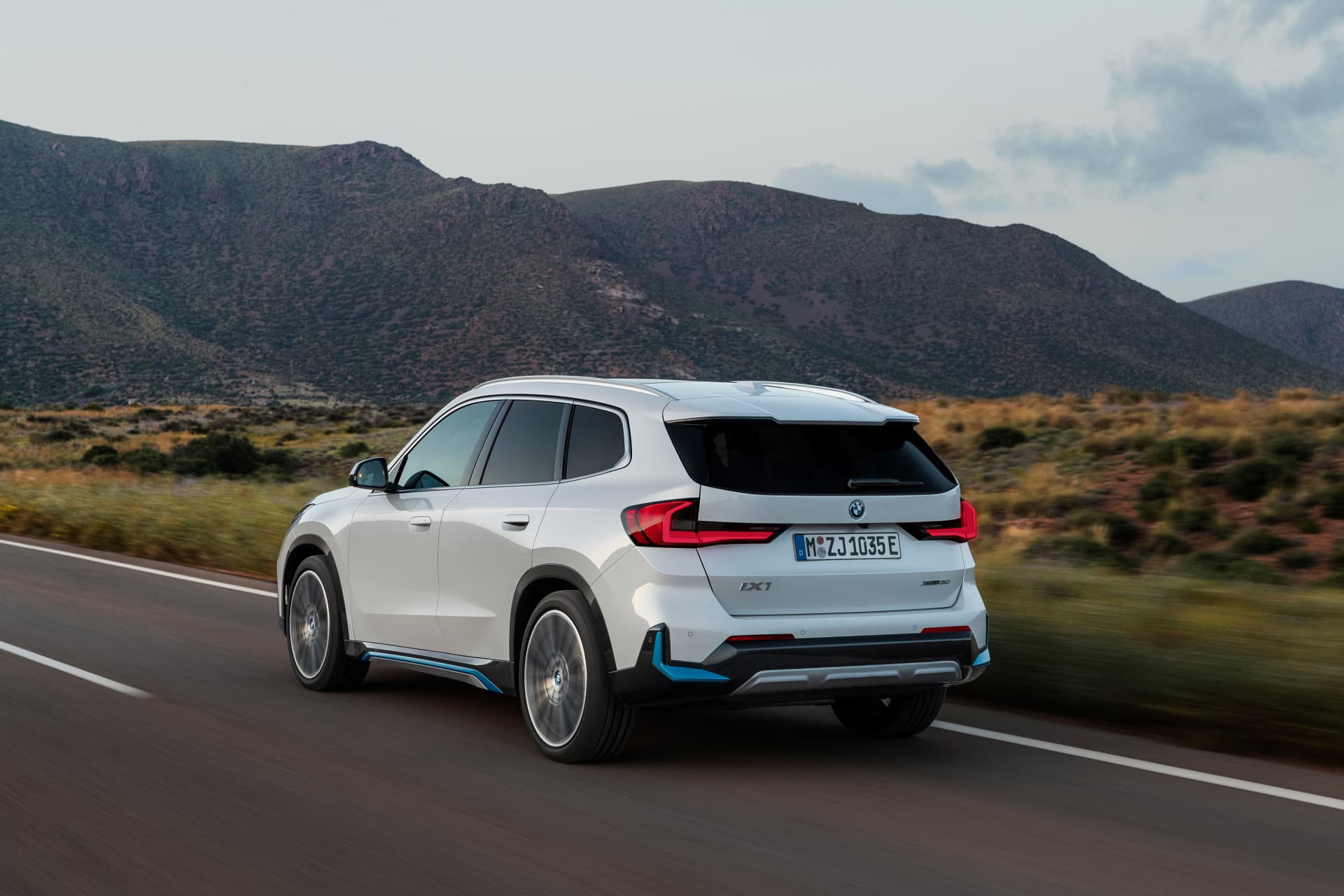 Vista dinámica del BMW X1 circulando por una carretera con paisaje montañoso.