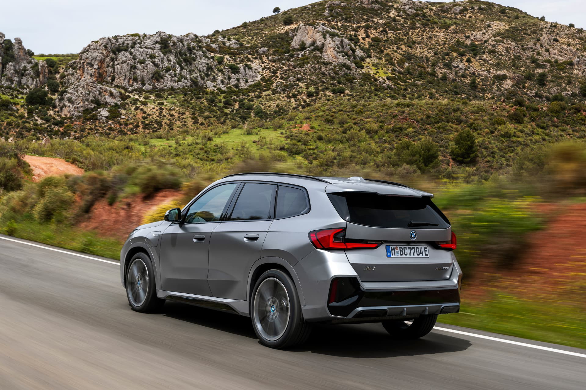 Vista dinámica del BMW X1 en carretera, destacando su diseño lateral y trasero.