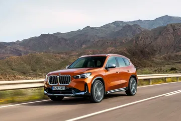 Vista dinámica del BMW X1 avanzando por carretera de montaña.