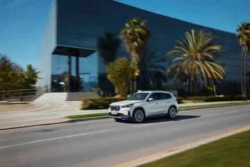 Vista lateral del BMW X1 en movimiento por una vía urbana.