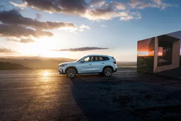 El BMW X1 muestra su perfil lateral con una puesta de sol al fondo