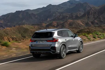 Perfil trasero del BMW X1 evidenciando su dinamismo y diseño robusto en carretera de montaña