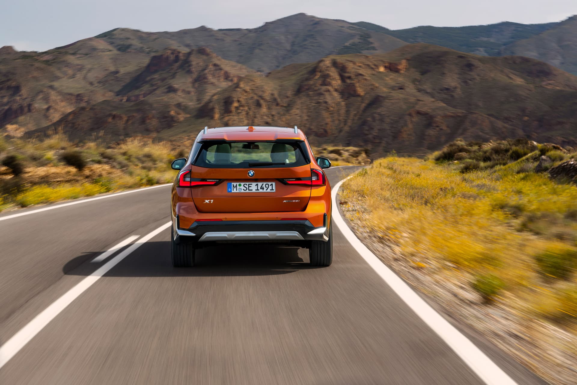 Vista trasera del BMW X1 en movimiento, destacando dinamismo y diseño.