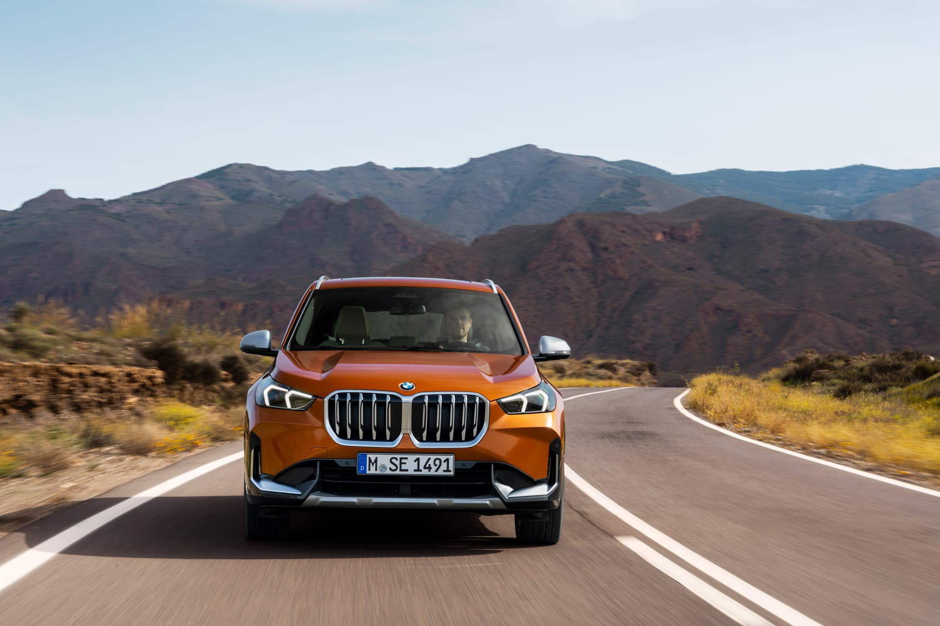 Vista frontal del BMW X1 en carretera, destacando su parrilla distintiva y faros LED.