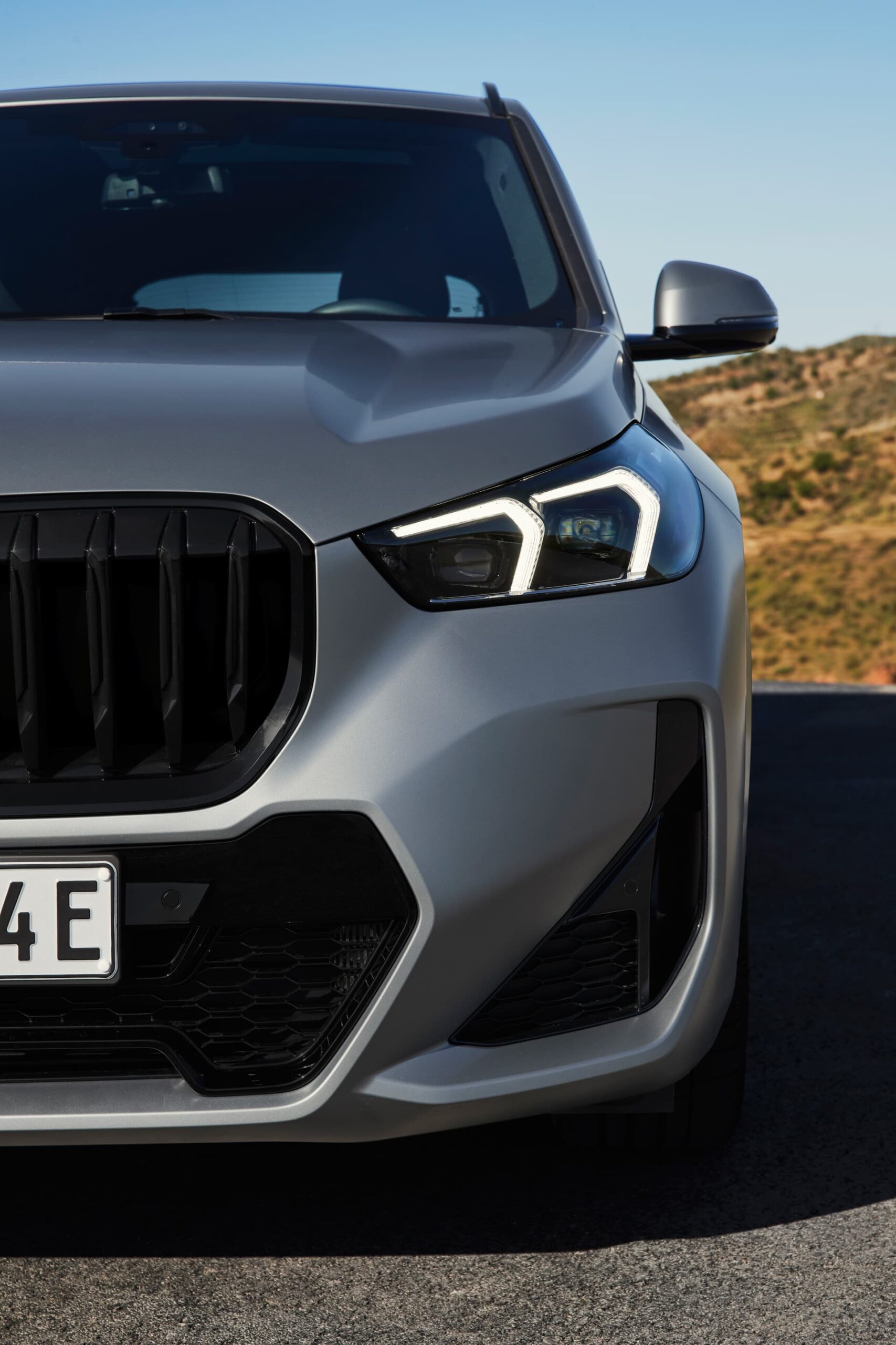 Vista focalizada en el diseño frontal y lateral del BMW X1, destacando su parrilla y faros.