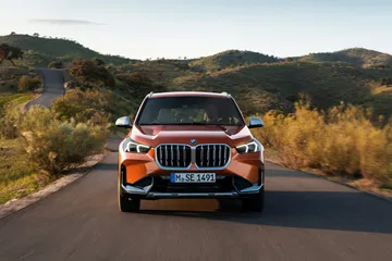 El BMW X1 muestra su robusta parrilla frontal y faros afilados en un entorno natural.