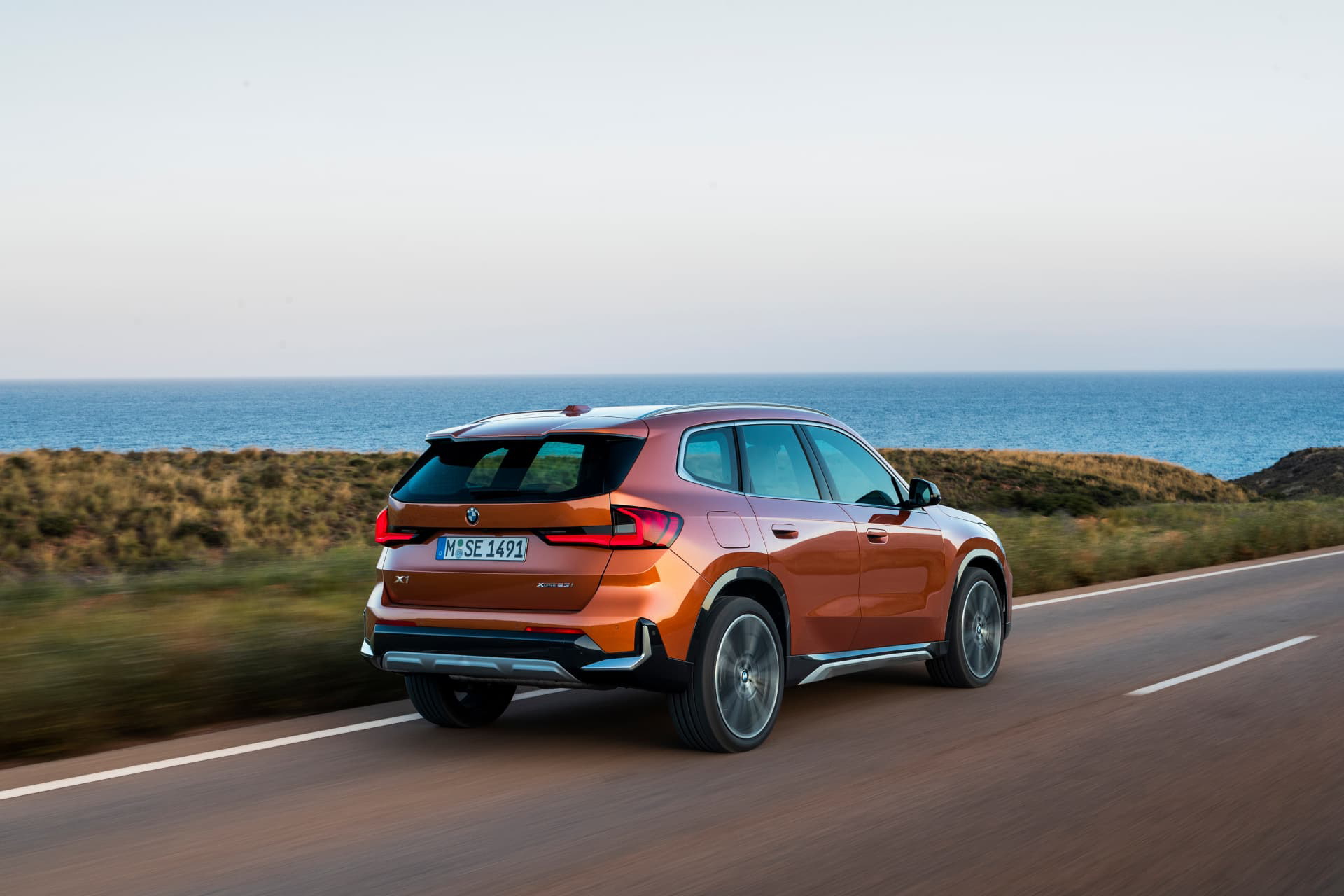 BMW X1 en movimiento con vista lateral y el océano de fondo