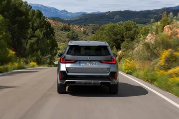 Vista trasera del BMW X1 en movimiento por carretera secundaria
