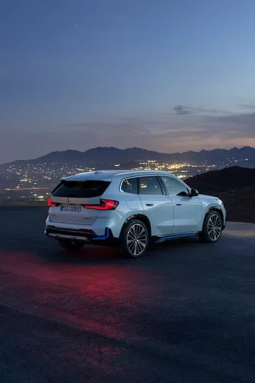 BMW X1 capturado con una vista trasera lateral en un ambiente nocturno.