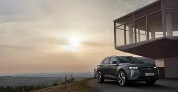 DS 7 capturado con un atardecer de fondo, destacando su diseño frontal y perfil lateral.