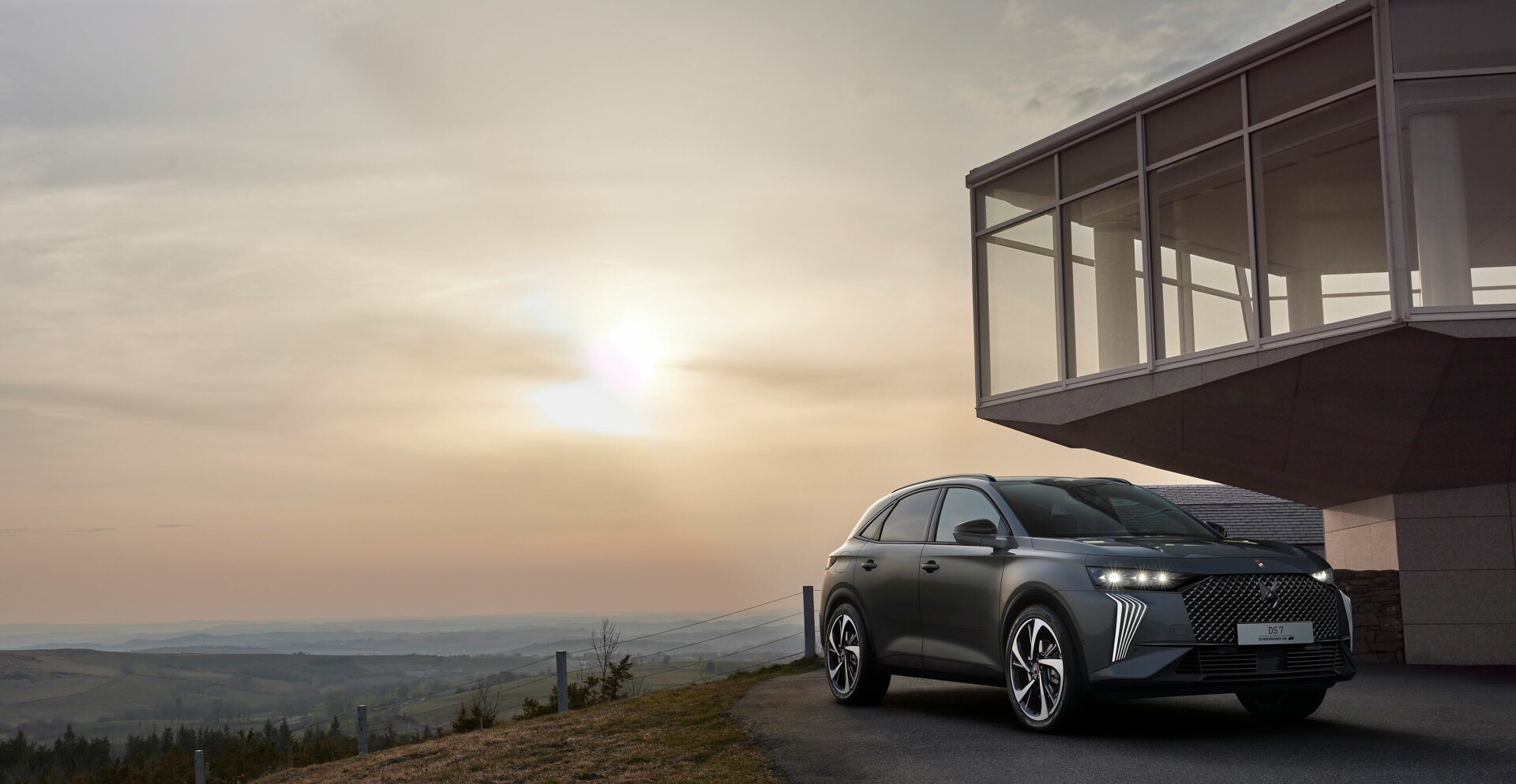 DS 7 capturado con un atardecer de fondo, destacando su diseño frontal y perfil lateral.