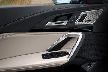 Vista del panel de la puerta con acabados en cuero y controles de ventanas.