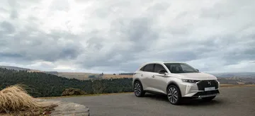 Vista lateral del DS 7 mostrando su línea dinámica y elegante bajo un cielo nublado.