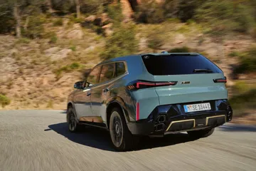Vista dinámica de la BMW XM mostrando su diseño trasero y perfil lateral.