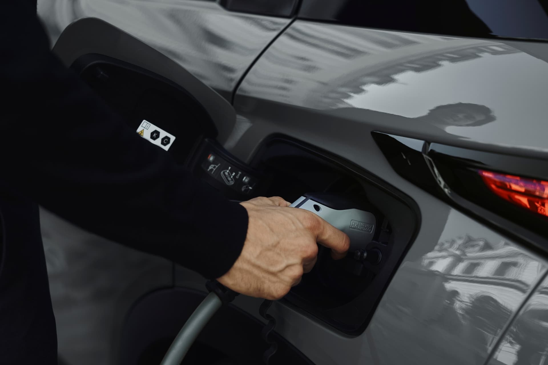Mano conectando el cargador al DS 3, destaca la tecnología eléctrica.
