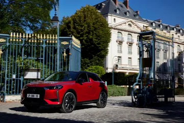 Vista lateral de un DS 3 rojo en un entorno urbano, destacando su diseño vanguardista.