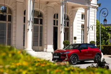 Un DS 3 rojo posa con distinción ante un entorno arquitectónico refinado.