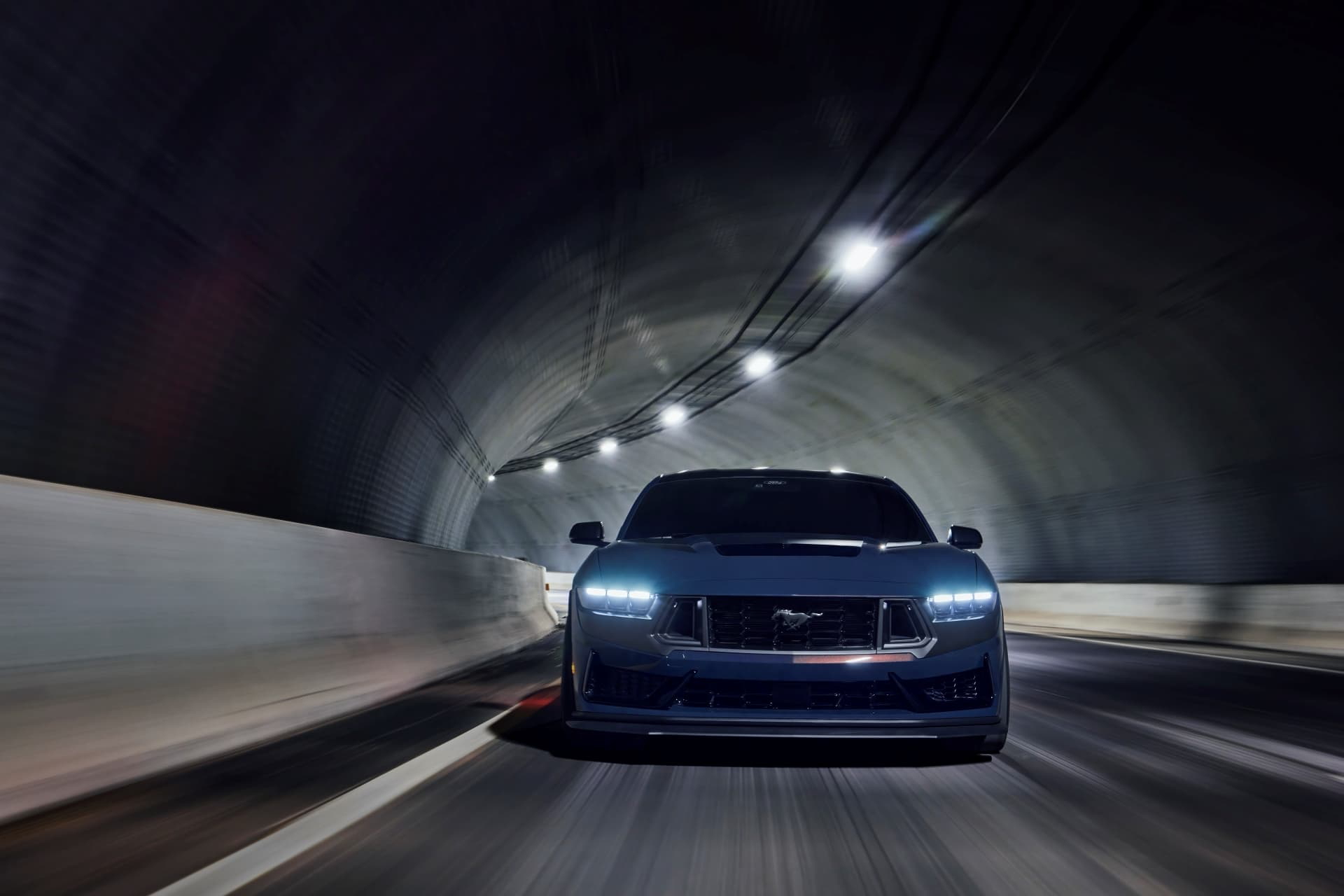 Vista agresiva del frontal de un Ford Mustang avanzando por un túnel iluminado.
