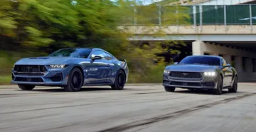 Dos Ford Mustang en acción, destacando su dinamismo y diseño lateral deportivo.