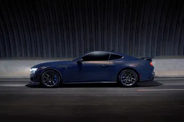 Vista lateral del Ford Mustang en una toma nocturna que destaca su diseño icónico y deportivo.