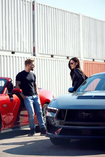 Vista lateral y delantera del Ford Mustang en dos tonalidades con personas al lado.