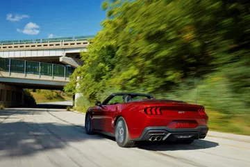Ford Mustang en movimiento captado desde un ángulo trasero-lateral.