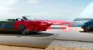Ford Mustang convertible en color rojo, perfil lateral con playa de fondo.